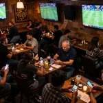 Engaged patrons placing bets on the QE8 platform at a lively sports bar, showcasing excitement and social interaction.